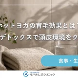 洗面台に置かれた白いタオルとヘアブラシ、水を注いだガラスのコップと観葉植物が並ぶ静かな静物イメージ