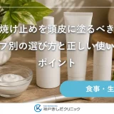 木のテーブルに並んだ日焼け止めのボトルとスプレー、パウダーブラシの静物イメージ