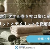 朝の寝室で、たたんだバスタオルを重ねた枕とリネンの寝具が並ぶ静物イメージ