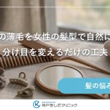 明るい窓辺の台に置かれた木製のコーム、細いヘアクリップ、たたんだ淡いタオルと小さな鏡の静物イメージ