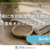 明るい木のテーブルに小さな手鏡とガラスの容器、麻のクロスと観葉植物が並ぶ静物イメージ